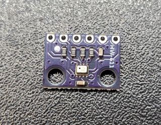 BMP280 barometric sensor on a small purple breakout board with a row of six pin holes