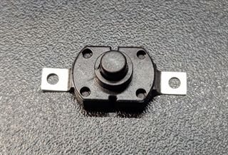 Small black self-locking push switch with two metal mounting tabs