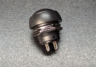 Round black panel-mount momentary push button with a threaded barrel and two solder tabs
