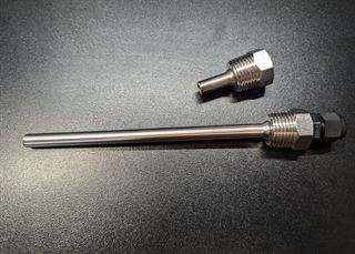 Stainless steel thermowell with a threaded hex fitting and a black cable gland, shown alongside a spare fitting