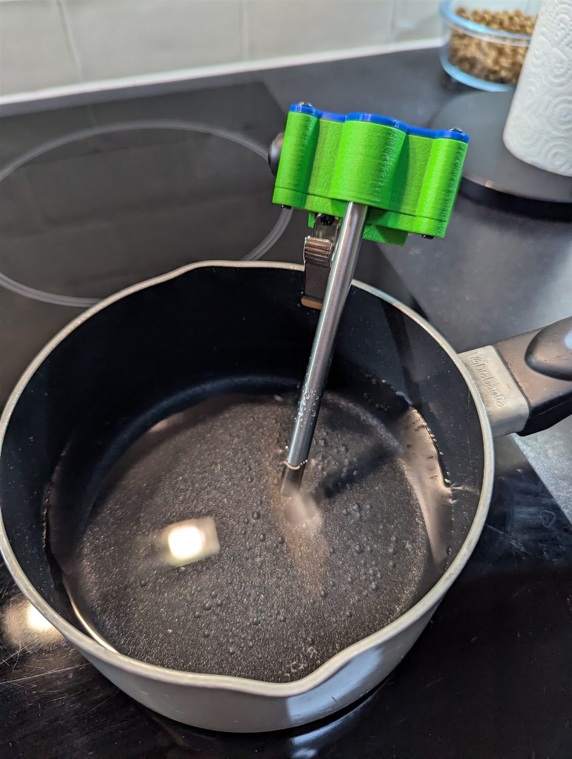 PotWatch clipped to the rim of a saucepan, its stainless probe down in the still water